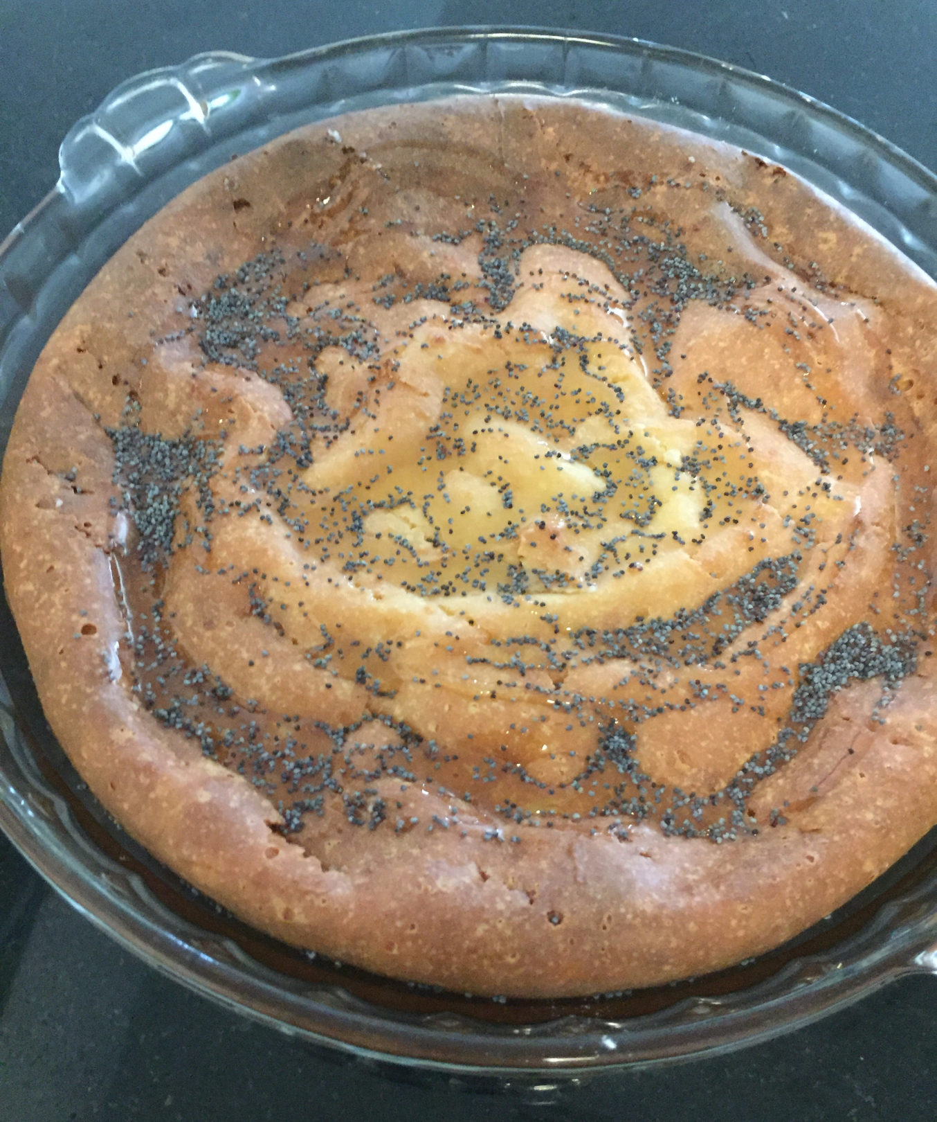 Round cake sprinkled with sesame seeds in a baking dish.